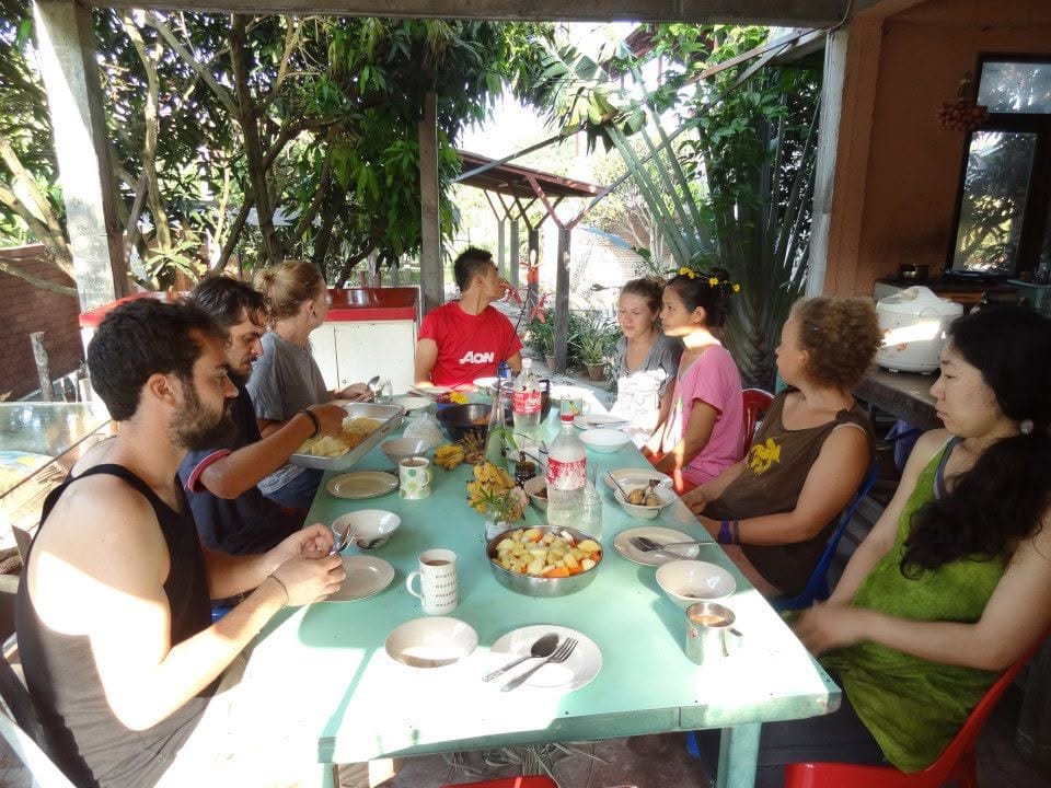 Course participants sharing a meal together at a long table under a shaded outdoor roof